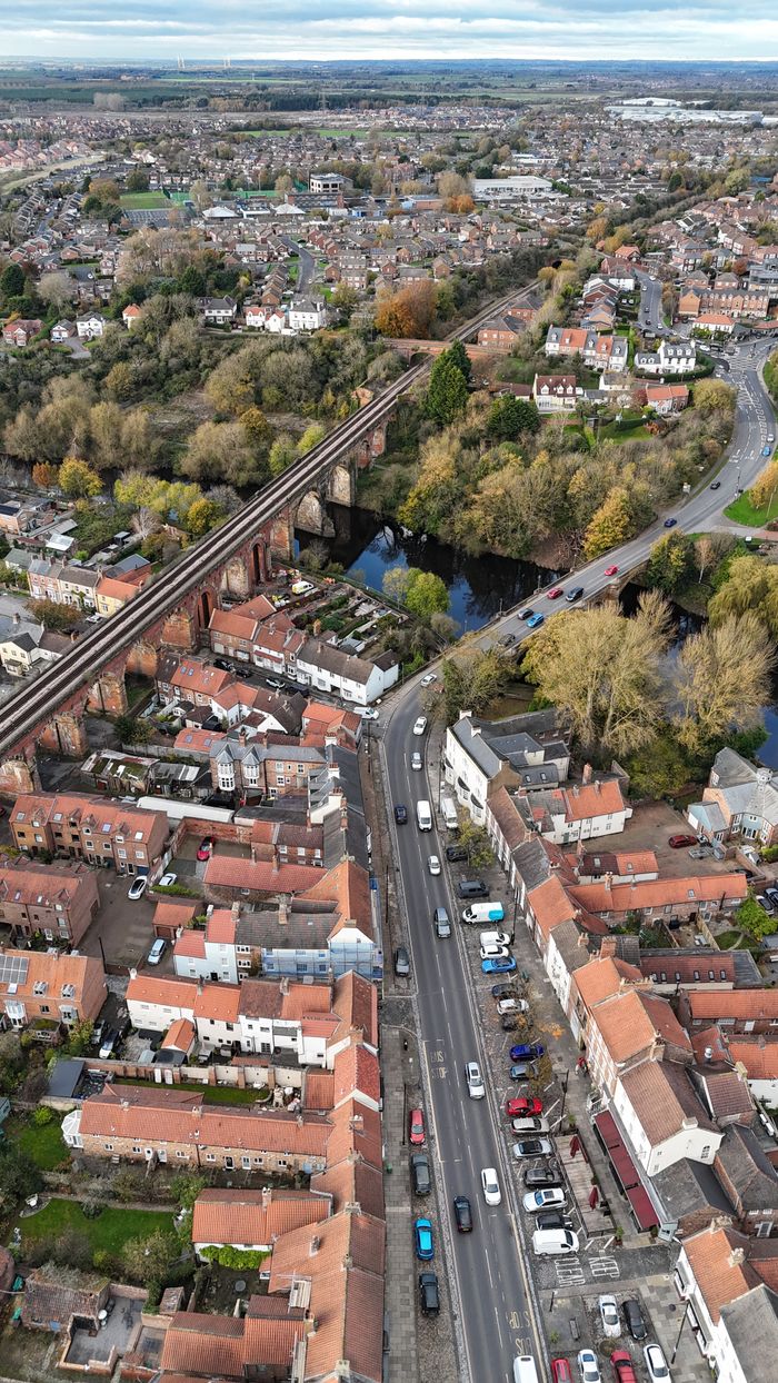 birthday-party-04 A scenic aerial view showcasing a railway viaduct over a residential area during fall season.