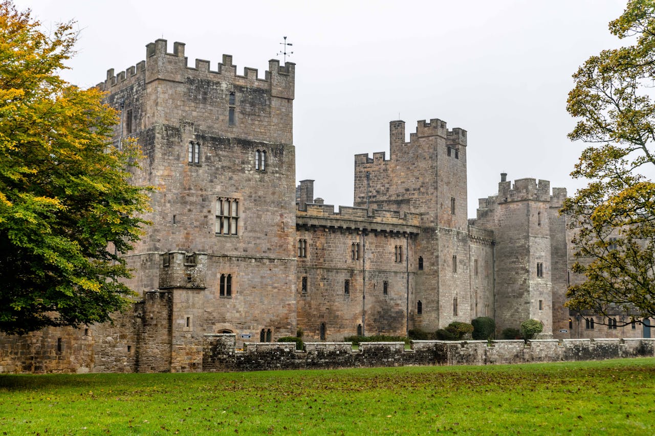 Explore the medieval charm of Raby Castle surrounded by lush autumn foliage in England.